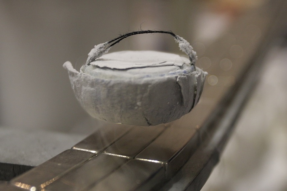 Meissnerův jev - supravodič levituje nad magnetem. Ve vzduchu ho drží magnetické pole, které nemůže proniknout do nitra supravodiče, foto Henry Mühlpfordt, CC BY-SA 3.0, https://creativecommons.org/licenses/by-sa/3.0, via Wikimedia Commons.