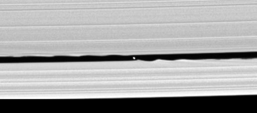 Saturnův měsíc S/2005 S1 na snímku sondy Cassini (foto NASA/JPL/Space Science Institute). Vlnitý okraj Keelerovy mezery je způsobem rušivým vlivem gravitace tohoto měsíce.